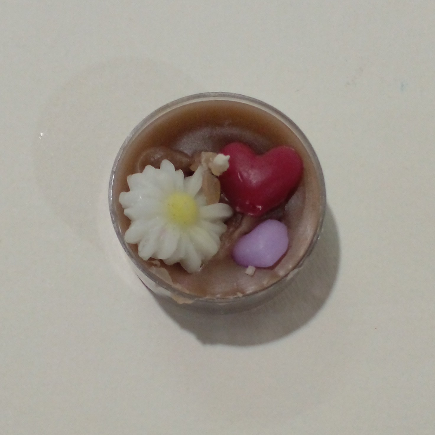 شمع وارمر دست ساز رنگ قهوه ایی با طرح گل بابونه و قلب های بنفش و قرمز در ابعاد دو سانتی و قطر چهار سانتی وزن 17 گرمی