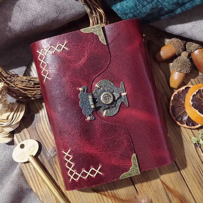 کلاسور چرمی 21 در 16  با چرم گاوی افکتی زرشکی ، یک جیب داخل جلد و دو ورقه چرمی برای زیر و روی کاغذا و صد برگ کاغذ خطدار 